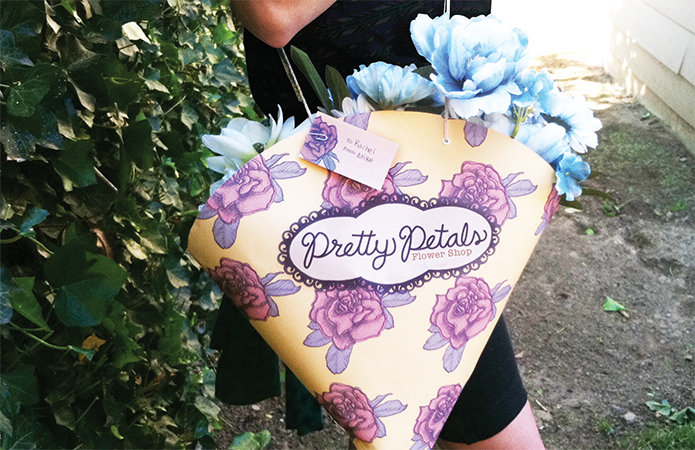 Woman holding bouquet packaging over her shoulder.